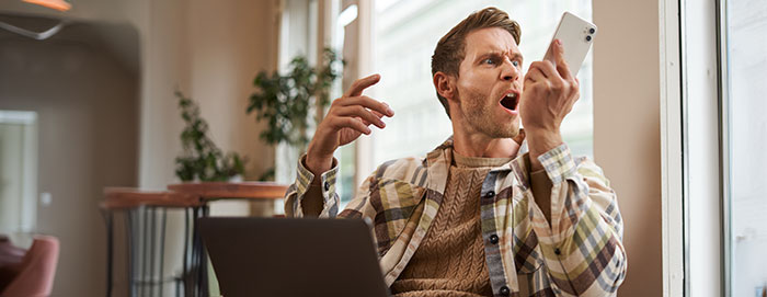Young man reacting with frustration while looking at phone during virtual date with young woman single dad.
