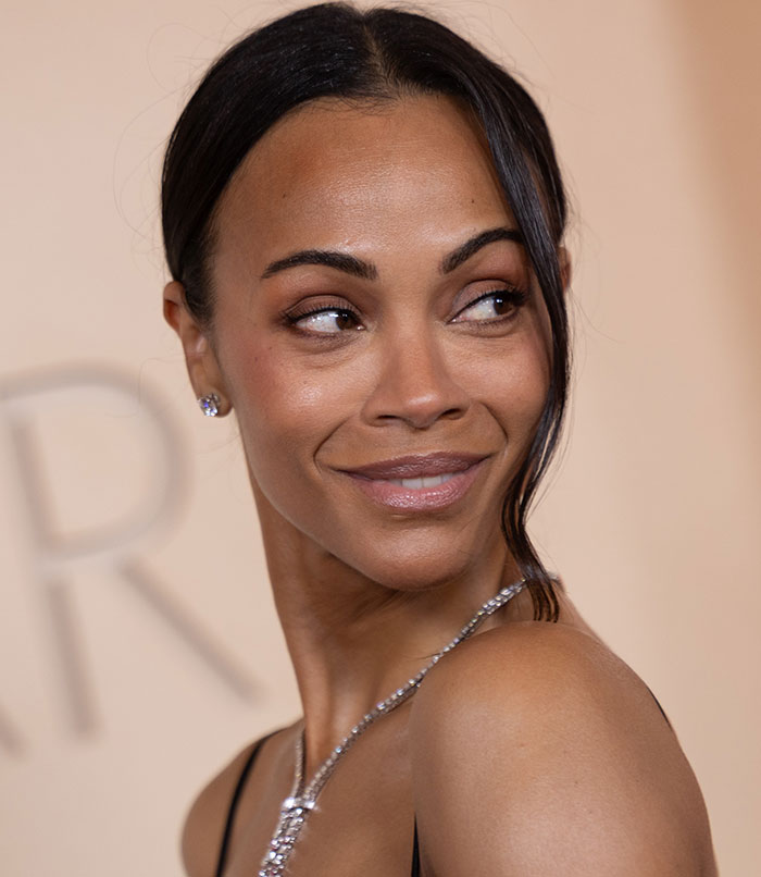 Woman with tired eyes looking sideways, showcasing youthful face and natural expression at a formal event.