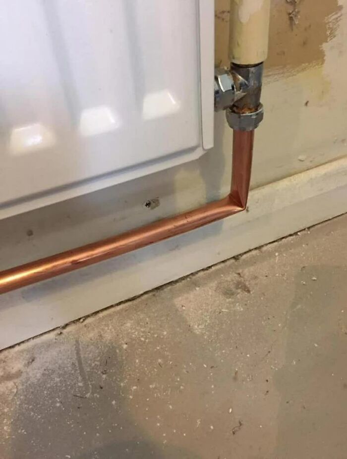 A copper pipe badly bent at a corner, connecting to a radiator. A weird image, making you go hmmm.