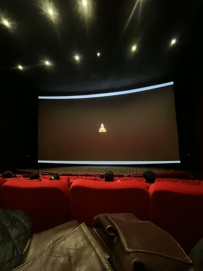 A movie screen in a dark theater shows the VLC media player cone icon, a truly weird image.