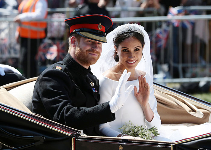 Prince Harry in military uniform and Meghan Markle in wedding dress waving from a carriage, highlighting their turbulent dynamic.