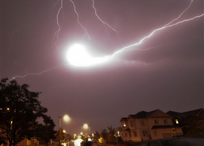 Lightning striking over a quiet neighborhood, illustrating moments that sound made up but are 100% real stories.