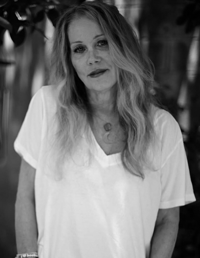 Black and white photo of Christina Applegate with long hair, wearing a white shirt, sharing update about her hospitalization details.
