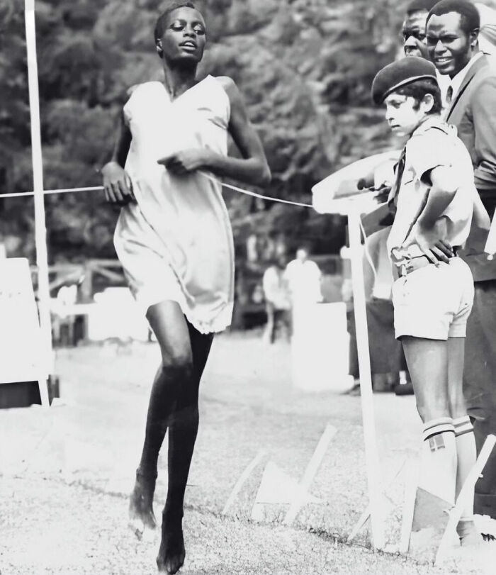 Runner approaching finish line during a race with spectators watching, captured in a striking black and white moment.