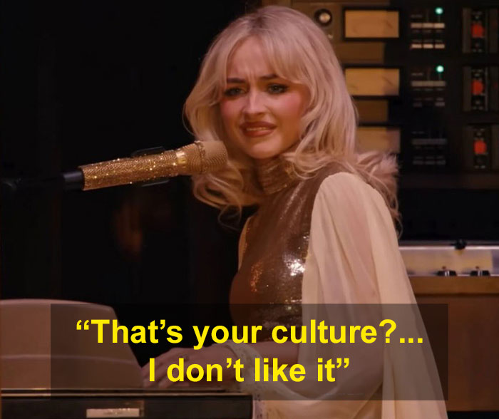 Female performer at Coachella 2026 with glittery microphone, making a cringe face during a live show moment.