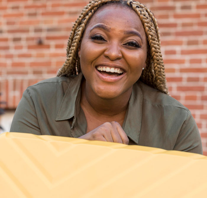 A smiling Black woman with blonde braids and a green shirt, looking happy. This image relates to favorite things about Black people.