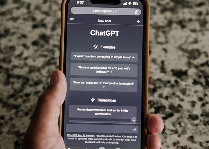 Smartphone screen showing ChatGPT interface with examples and capabilities, highlighting dangers of technology use.