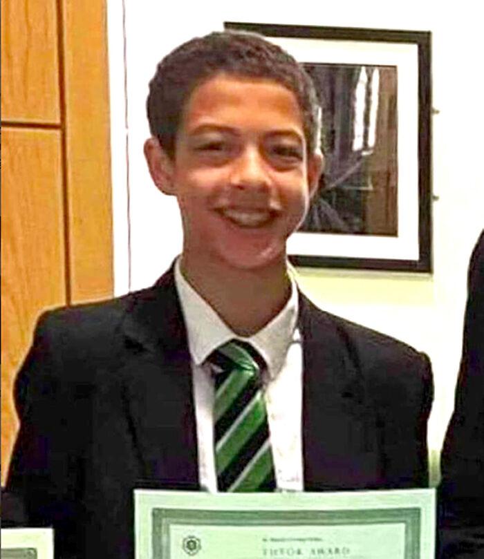 Teen boy in a suit and green striped tie smiling and holding a certificate, related to creepy and mysterious sleepless thoughts.