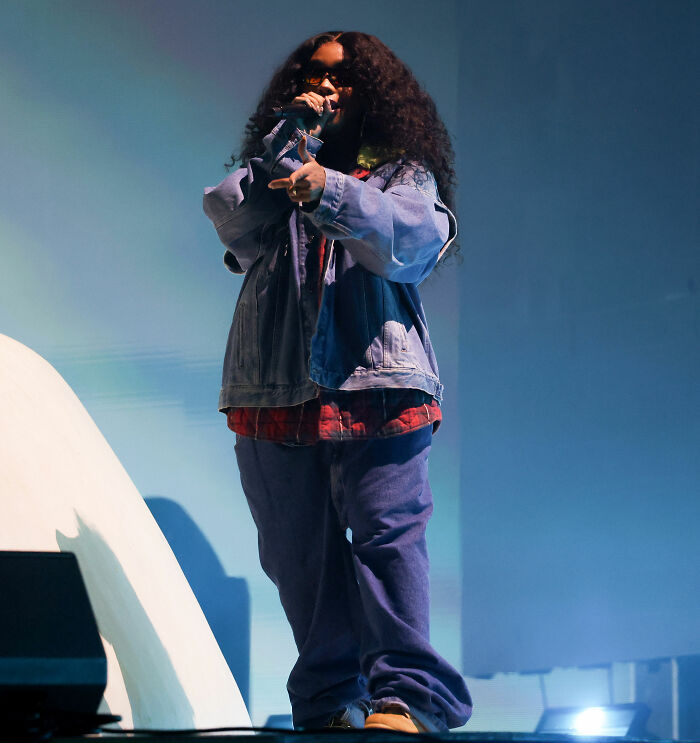Performer on stage at Coachella wearing oversized denim jacket and baggy pants, showcasing festival fashion style.