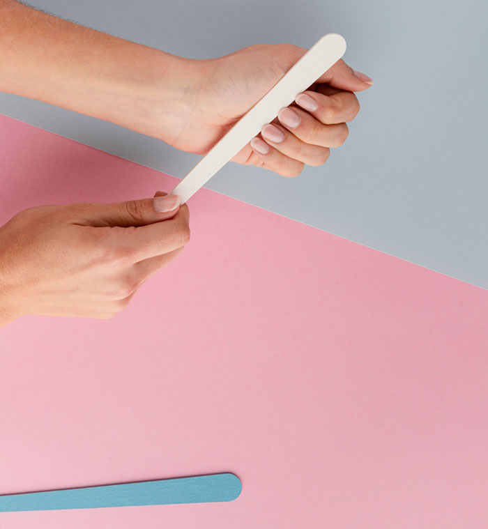 Woman filing nails, beauty facts, on a pink and blue background.