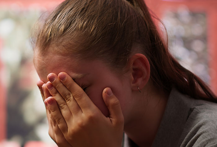 Upset young girl covering her face after teacher grabs kids in front of mom during a tense school incident.
