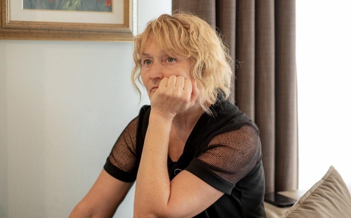 Woman thoughtfully sitting indoors, reflecting on friendship and betrayal after a painful experience involving a boy.