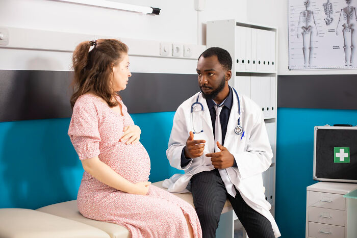 Pregnant woman consulting with a doctor in a medical office discussing random facts about their bodies.