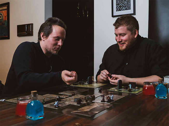 Two men playing board game, sharing a fun moment highlighting ex-girlfriend cheats on guy story.
