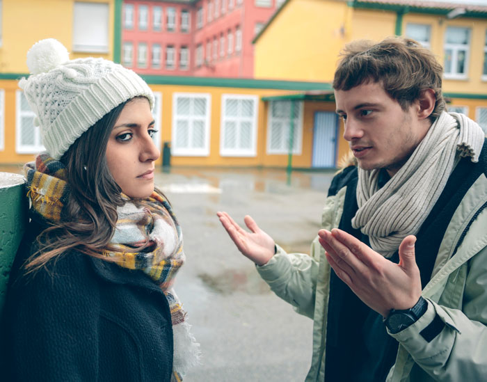Woman looking frustrated while man explains something outdoors, illustrating things women are tired of explaining to men.