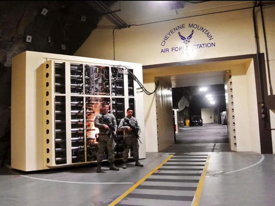 Two armed guards stand before Cheyenne Mountain Air Force Station's entrance, showcasing its toughest security, making it off limits.