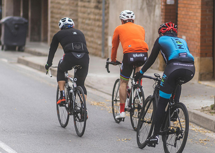 Three cyclists wearing helmets and athletic gear riding on a street, highlighting activities more dangerous than they seem.