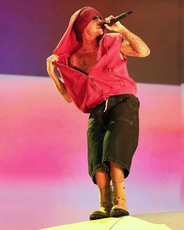 Performer on stage wearing an oversized red hoodie, black shorts, and beige boots showcasing Coachella weekend 2 fashion fails.