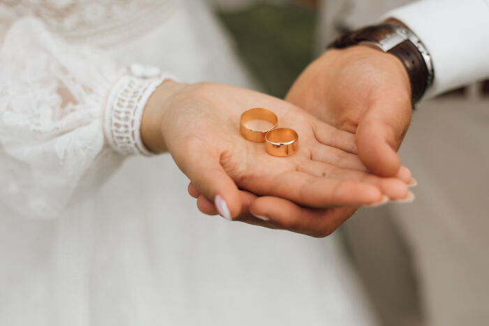 Hands holding wedding rings symbolizing guests witnessing a future breakup at a wedding ceremony.