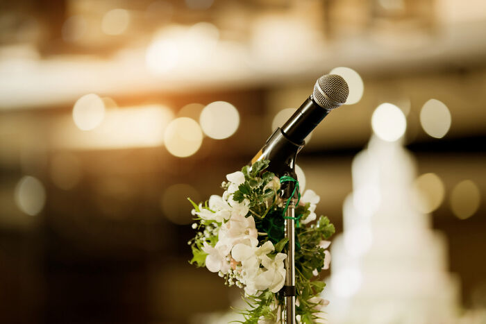 Microphone decorated with flowers at a wedding venue capturing stories from guests witnessing a future breakup.