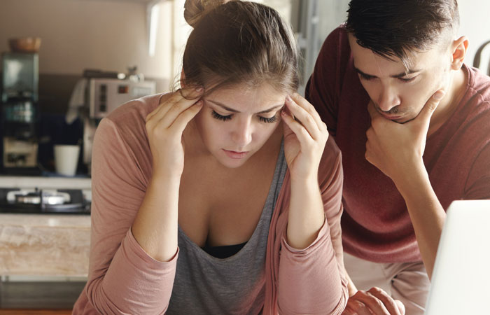 Stressed woman and man looking at a laptop, reflecting on teacher grabs kids situation called out by mom.
