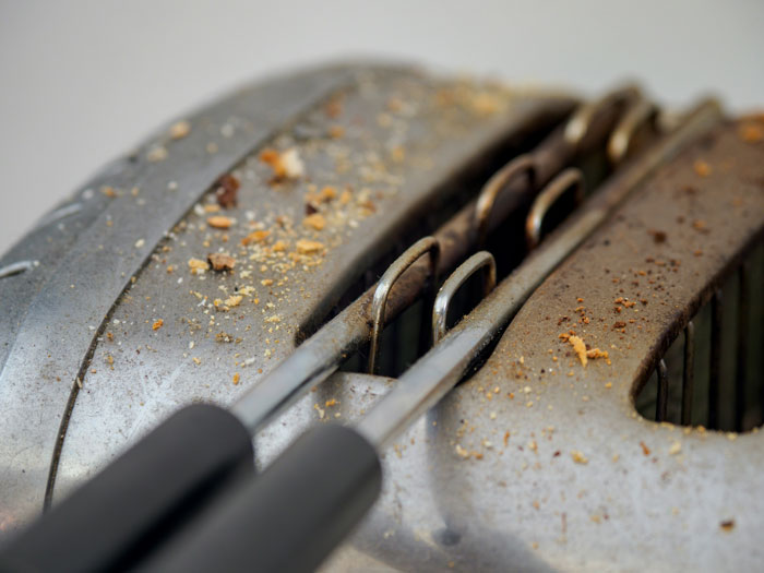 Close-up of a dirty toaster with crumbs, showing the dumb side of everyday appliances or dating choices.