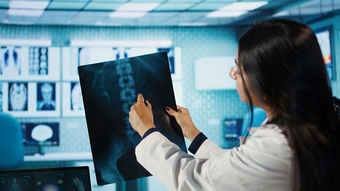 Female doctor examining spinal X-ray in a medical office, highlighting random facts people learned about their bodies after visits.