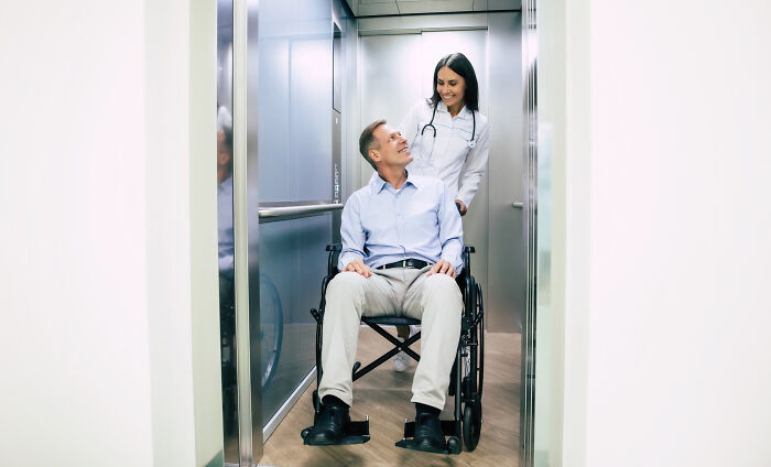 A doctor pushing a smiling male patient in a wheelchair from an elevator. Wildest rumours.