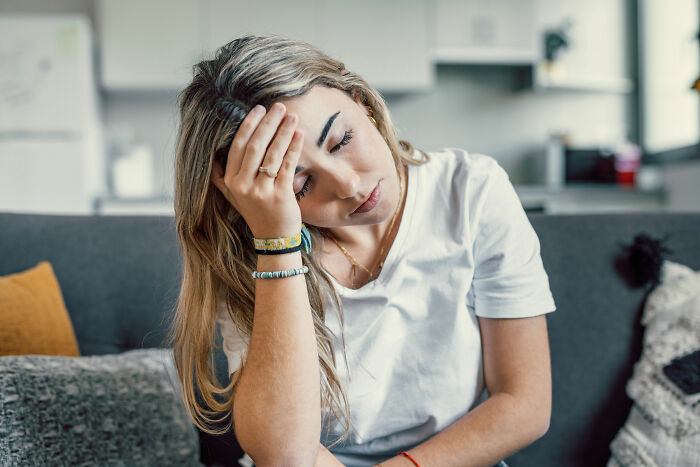 Woman looking frustrated sitting on a couch, representing things women are tired of explaining to men.