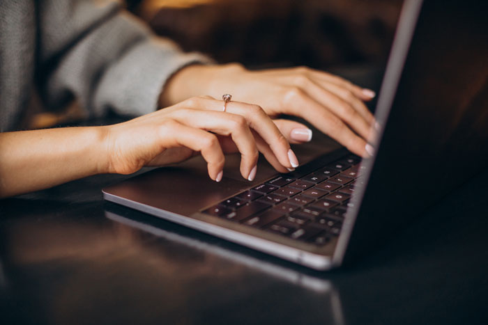 Person typing on a laptop keyboard illustrating stories of petty karma served to their manager in a workplace setting.