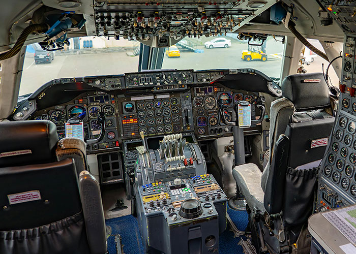 Inside a large airplane cockpit with numerous dials, buttons, and levers. People got exclusive access to this complex flight deck.