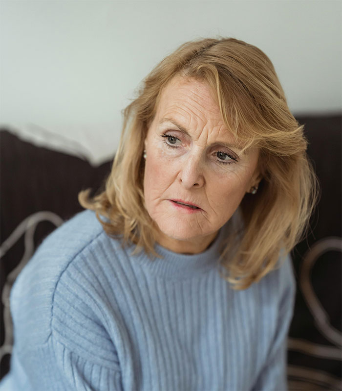 Woman with concerned expression sitting indoors, sharing a crazy story about her mom’s dramatic life events.