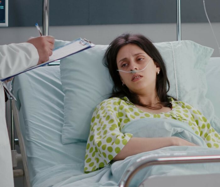 Ill patient in bed with nasal cannula, doctor taking notes. Reflects challenging things medical workers witnessed.