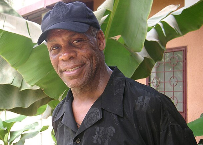 Actor Danny Glover smiling outdoors near large green leaves, highlighting beloved celebrities not that nice in real life.