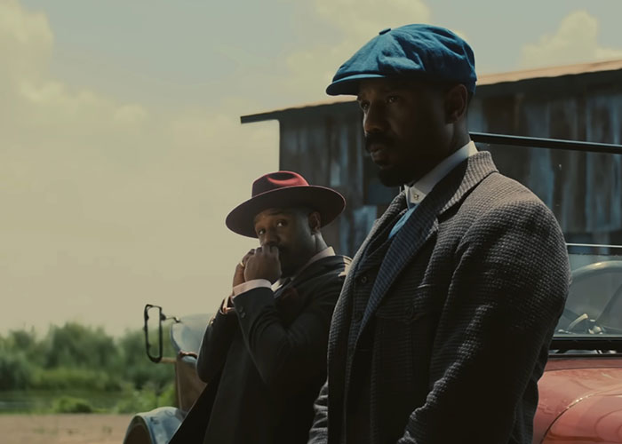 Two men in vintage attire standing by an old car, symbolizing signs the economy is not doing well.