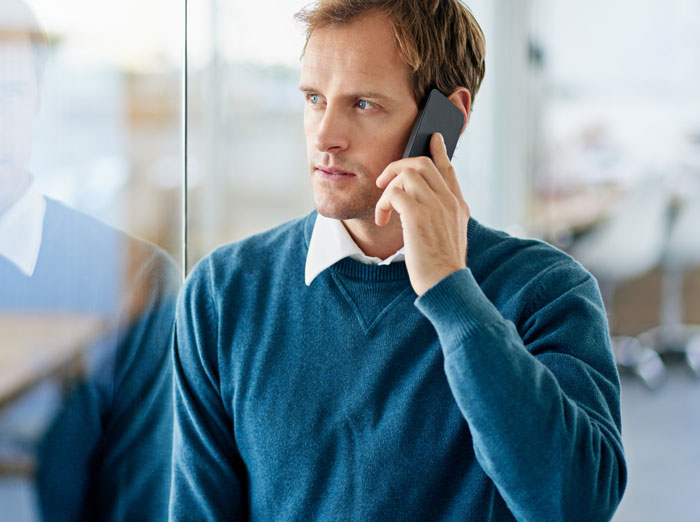Man on phone, looking thoughtful, considering action against toxic bosses.