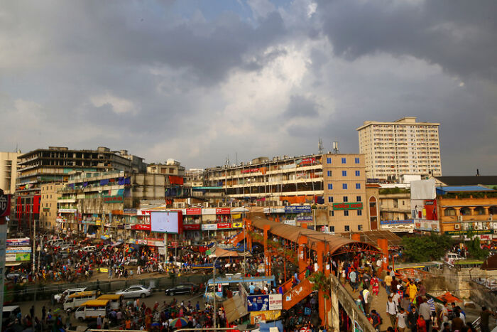 Dense city with crowded streets, pedestrian overpass, numerous buildings, and shops, representing countries with worst work-life balance.