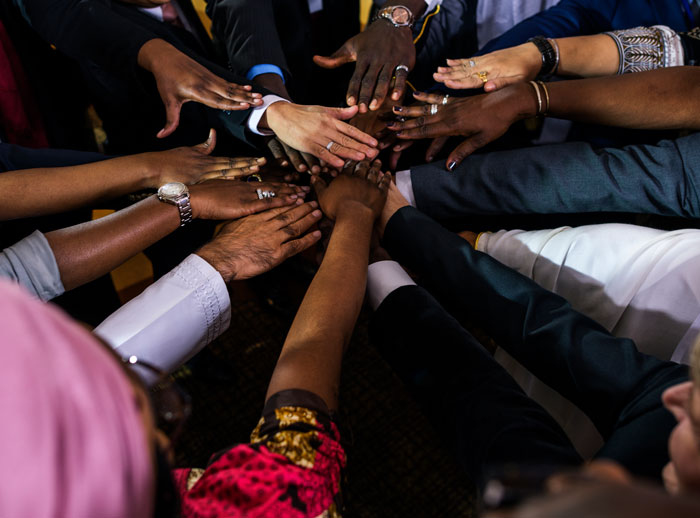 Diverse hands, including white people and Black people, stacked in a powerful symbol of unity and collaboration.