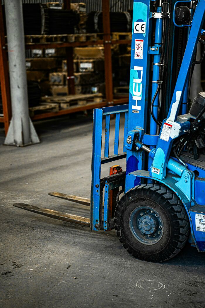 A blue forklift in a warehouse setting, highlighting potential workplace incidents and safety concerns.