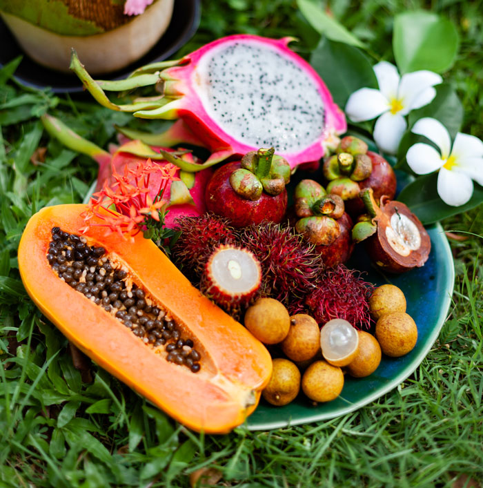 Vibrant plate of tropical fruits like papaya, dragon fruit, mangosteen, rambutan, and longan. Perfect for when people saw how dumb their person they're dating was.