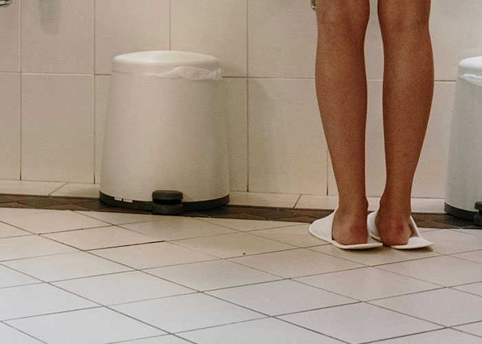 Person standing on slippery bathroom floor near trash cans illustrating dangers that seem minor but are risky.