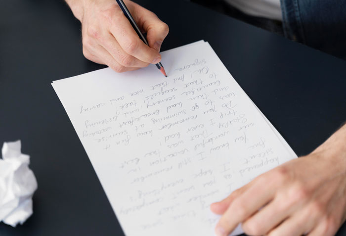 Person writing a letter, crumpled paper nearby, perhaps plotting revenge against toxic bosses.