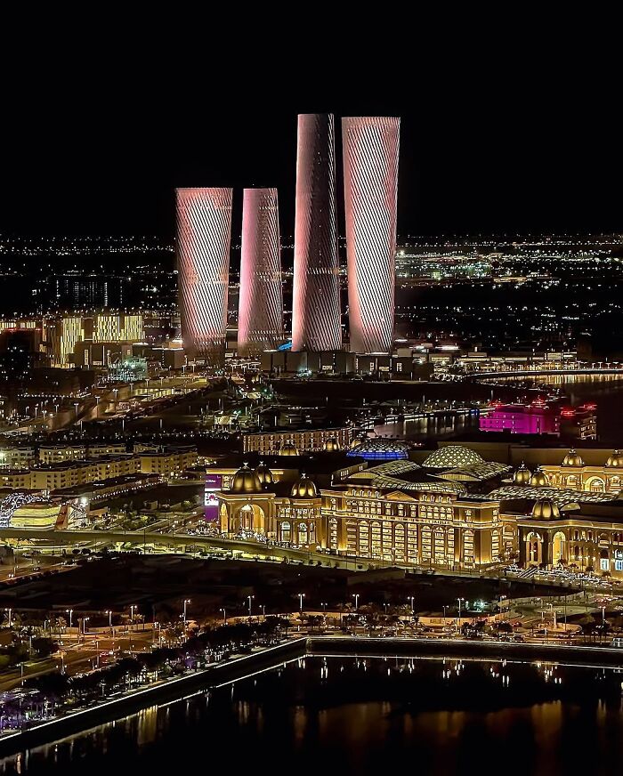 Aerial night view of a modern city with illuminated skyscrapers and traditional architecture, symbolizing urban life affecting work-life balance.