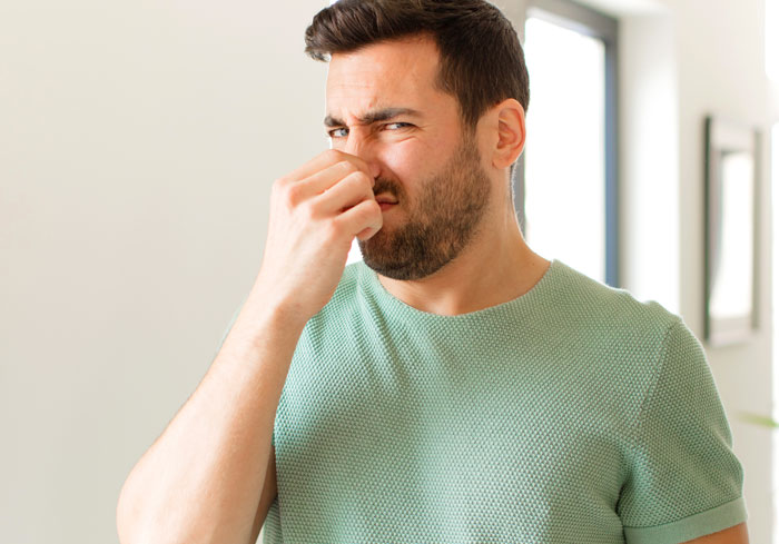 A man with a disgusted expression, pinching his nose, reacting to gross office stories.