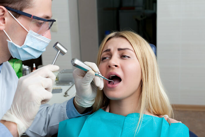 Dentist examining patient’s mouth with dental tools, highlighting random facts about bodies discovered during doctor visits.