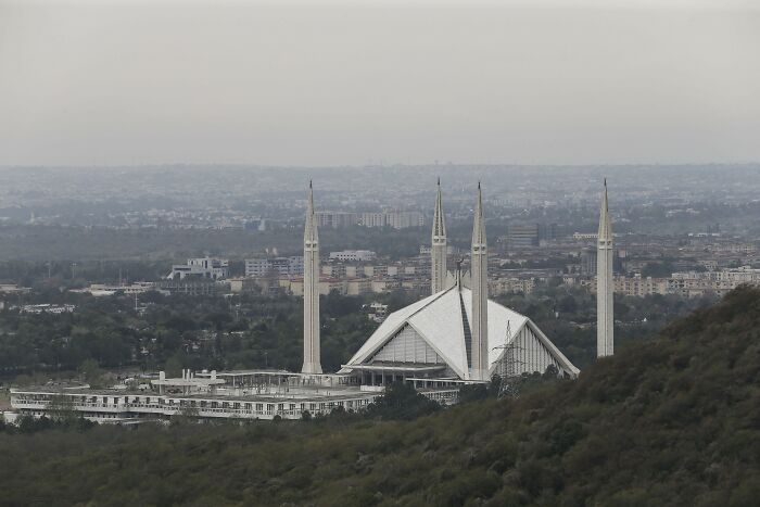 Faisal Mosque, Islamabad, Pakistan, seen from afar, with a hazy city in the background. Considering global Work-Life Balance.