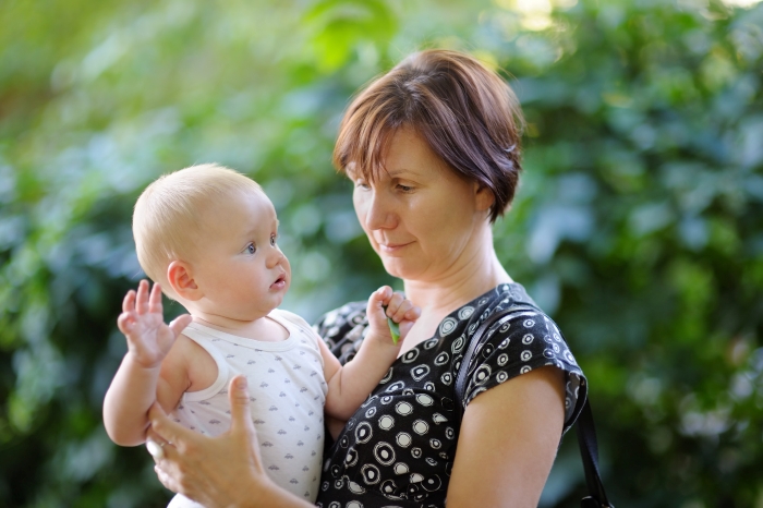 Woman holding baby outdoors with a concerned expression illustrating mom&rsquo;s creepy behavior and psychotic doubts.