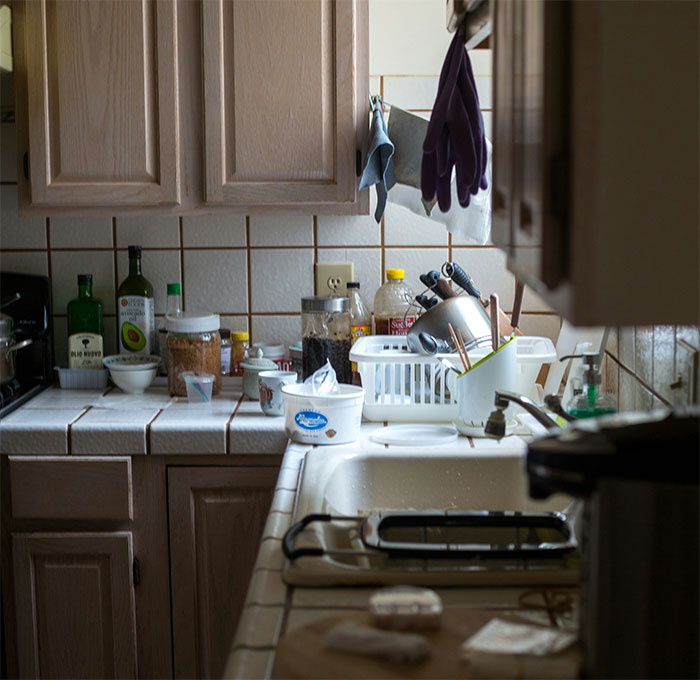 Cluttered kitchen countertop with dishes and utensils drying, illustrating a woman’s crazy mom story like a soap opera.