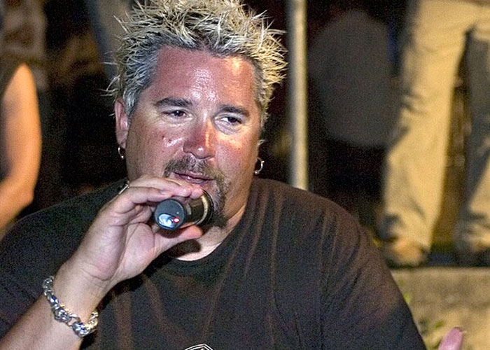 Celebrity speaking into a microphone at an event, representing beloved celebrities that are not that nice in real life.