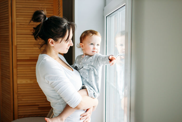Mother holding baby pointing outside near window, symbolizing red flags and instant regret from disastrous first dates.